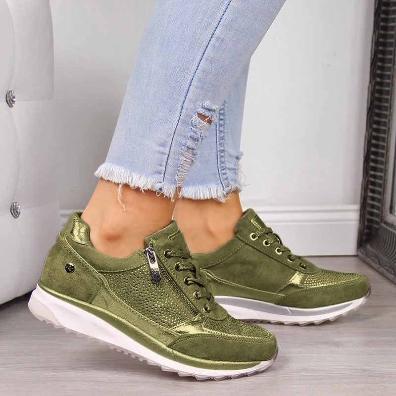 Chaussures de sport vertes pour femme, avec fermeture éclair et lacets, portées avec un jean déchiré. Style décontracté et moderne.