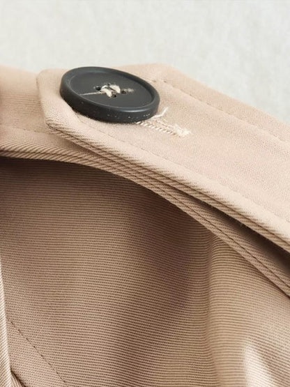 Beige jas met zwarte knoop en zichtbare stiksels close-up | Boutique Moda